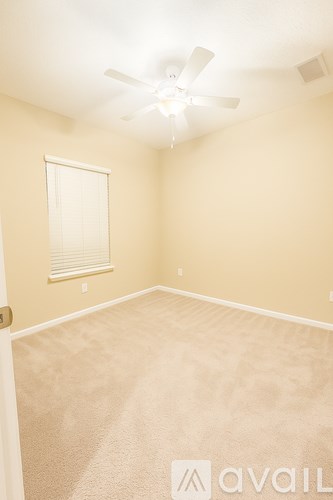 A room with a carpeted floor and a ceiling fan.