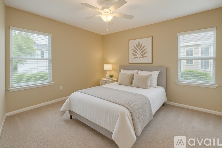 A bedroom with a bed, two pillows, a lamp, and a ceiling fan.