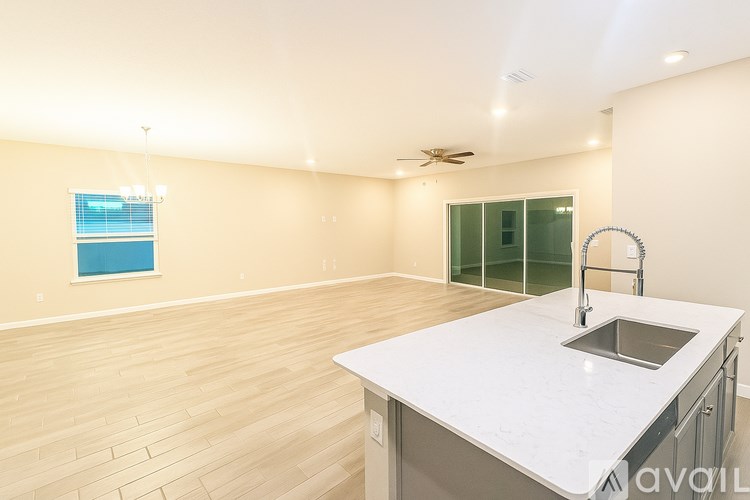 A kitchen with a white countertop and a window with blinds.