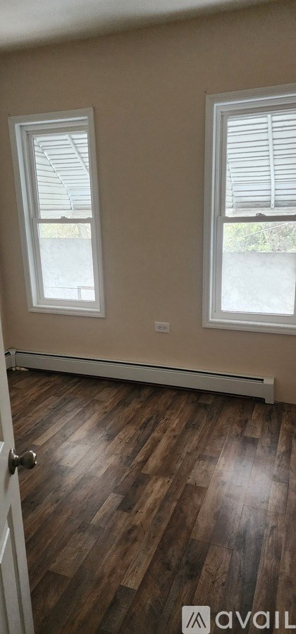 A room with wooden floors and two windows.