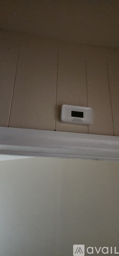 A white smoke detector is mounted on a beige wall.