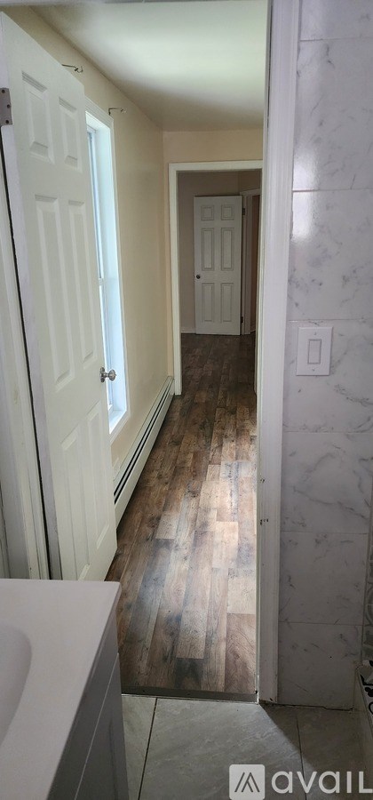A hallway with a wooden floor and white walls.