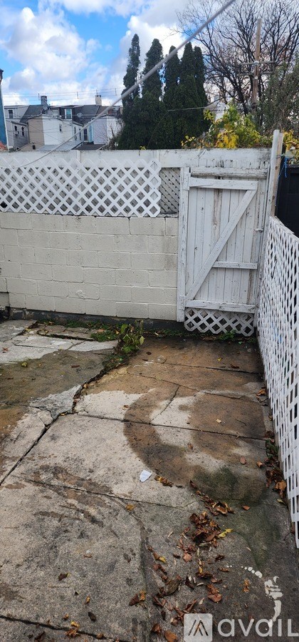 A white fence with a gate is in front of a wall.