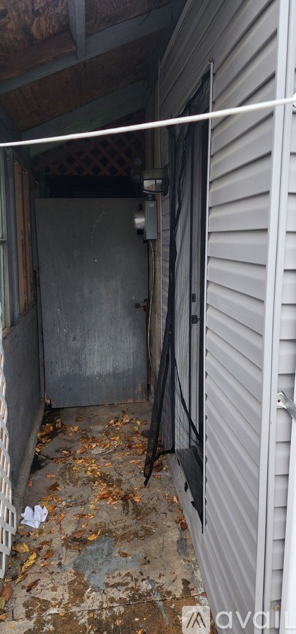 A dirty alley with a metal gate and a concrete wall.