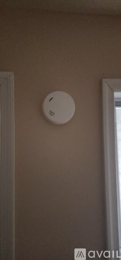 A white smoke detector is mounted on a beige wall.