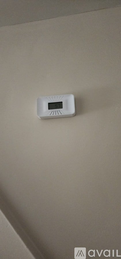 A white device is mounted on a beige wall.