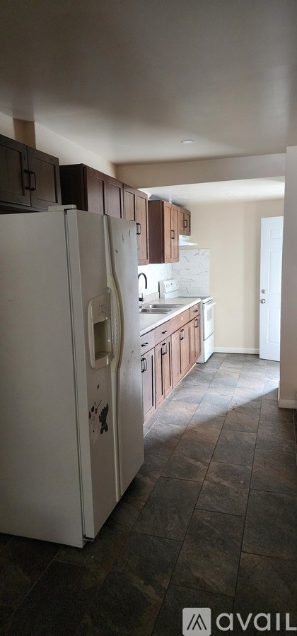 A kitchen with a white fridge and brown cabinets.