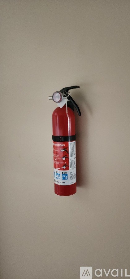 A red fire extinguisher is mounted on a beige wall.