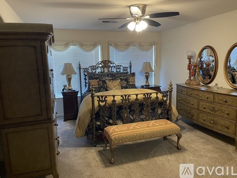 A bedroom with a large bed, a bench, and a dresser.