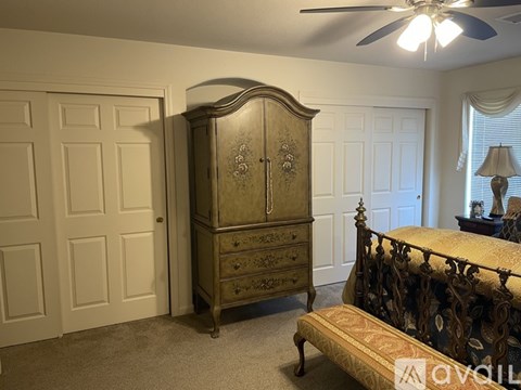 A bedroom with a bed, dresser, and a window with blinds.