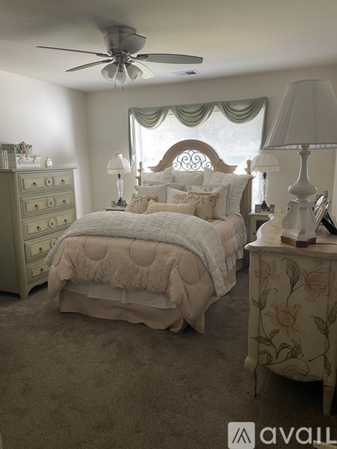 A bedroom with a large bed, a dresser, and a nightstand with a lamp.