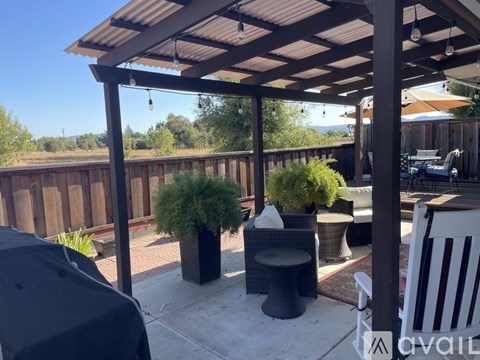 A patio with a black umbrella and a white chair.