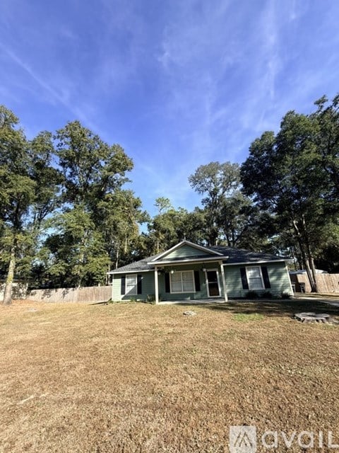 A house with a green roof is surrounded by trees and grass.