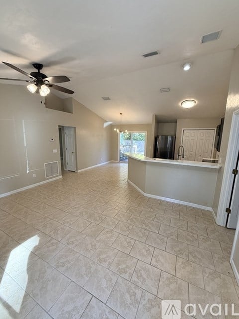A spacious room with a ceiling fan and tiled flooring.