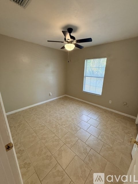 A room with a ceiling fan and tiled floor.