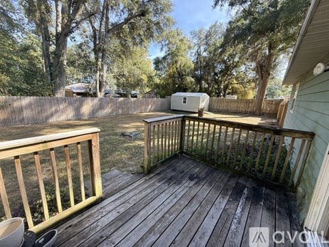 A wooden deck with a bench and a fence in the background.