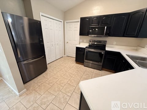 A kitchen with black cabinets and a white counter.