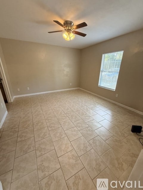 A room with a ceiling fan and tile flooring.