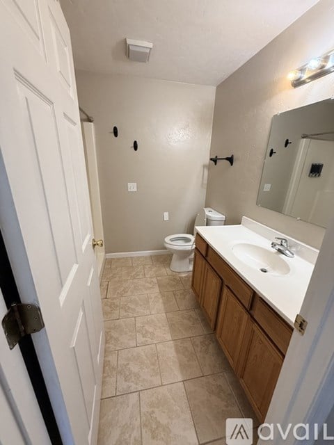 A bathroom with a toilet, sink, and mirror.