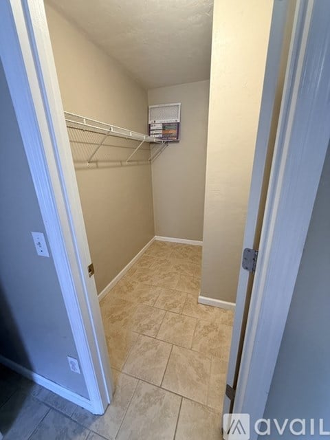 A small, empty room with a white door and a white fridge.