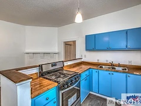 A kitchen with blue cabinets and a wooden counter top.