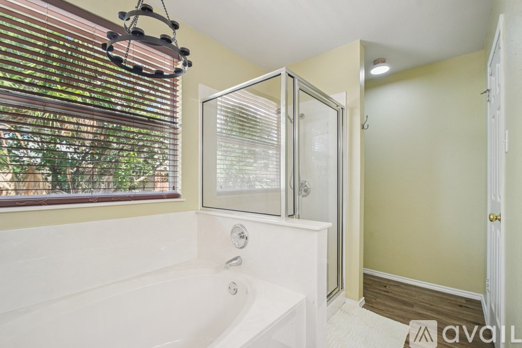 A bathroom with a white tub and a window with blinds.