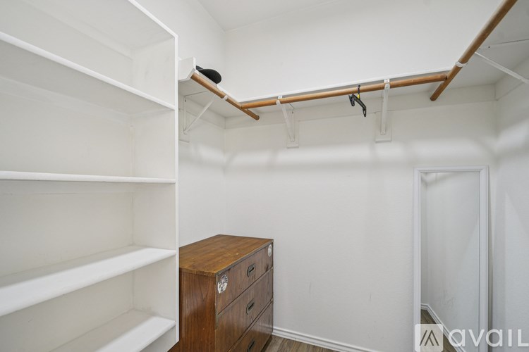 A white closet with a brown chest of drawers.