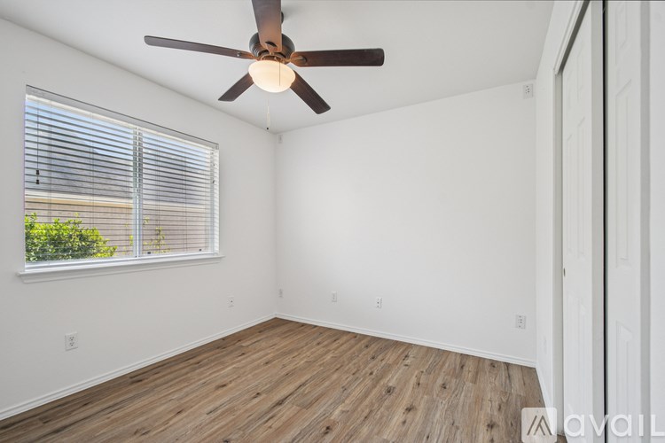 A room with a ceiling fan and wooden flooring.