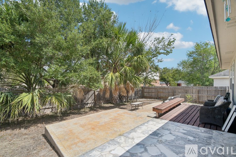 A backyard with a wooden deck and a variety of trees.