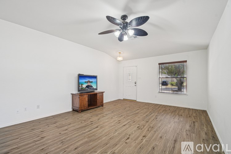 A room with a ceiling fan and a television on a wooden stand.