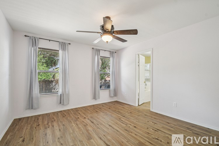 A room with a ceiling fan and wooden flooring.