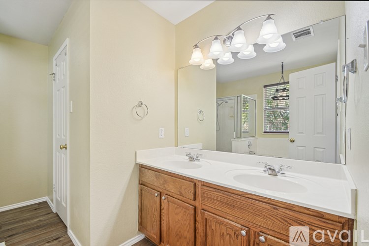 A bathroom with a white sink and wooden cabinets.