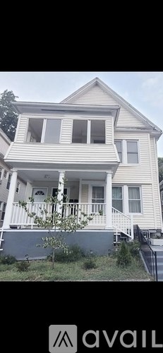 A two-story house with a white exterior and a balcony on the second floor.
