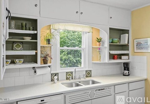 A kitchen with white cabinets and a window.