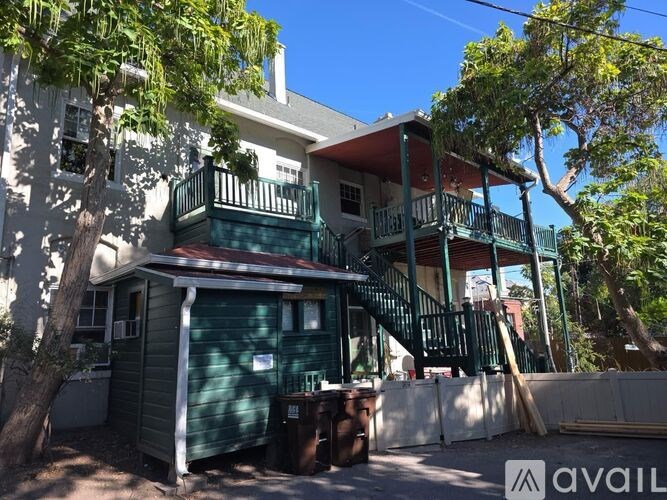 A house with a green balcony and a tree in front.