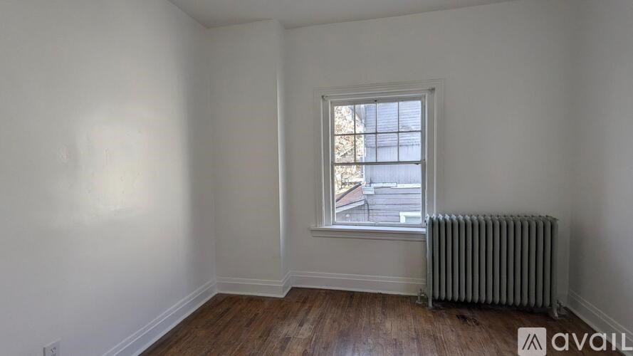 A room with a window and a radiator on the floor.