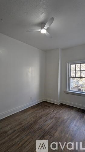 A room with a window and a fan on the ceiling.