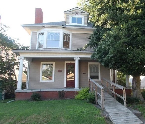 A house with a grey siding and a red door.