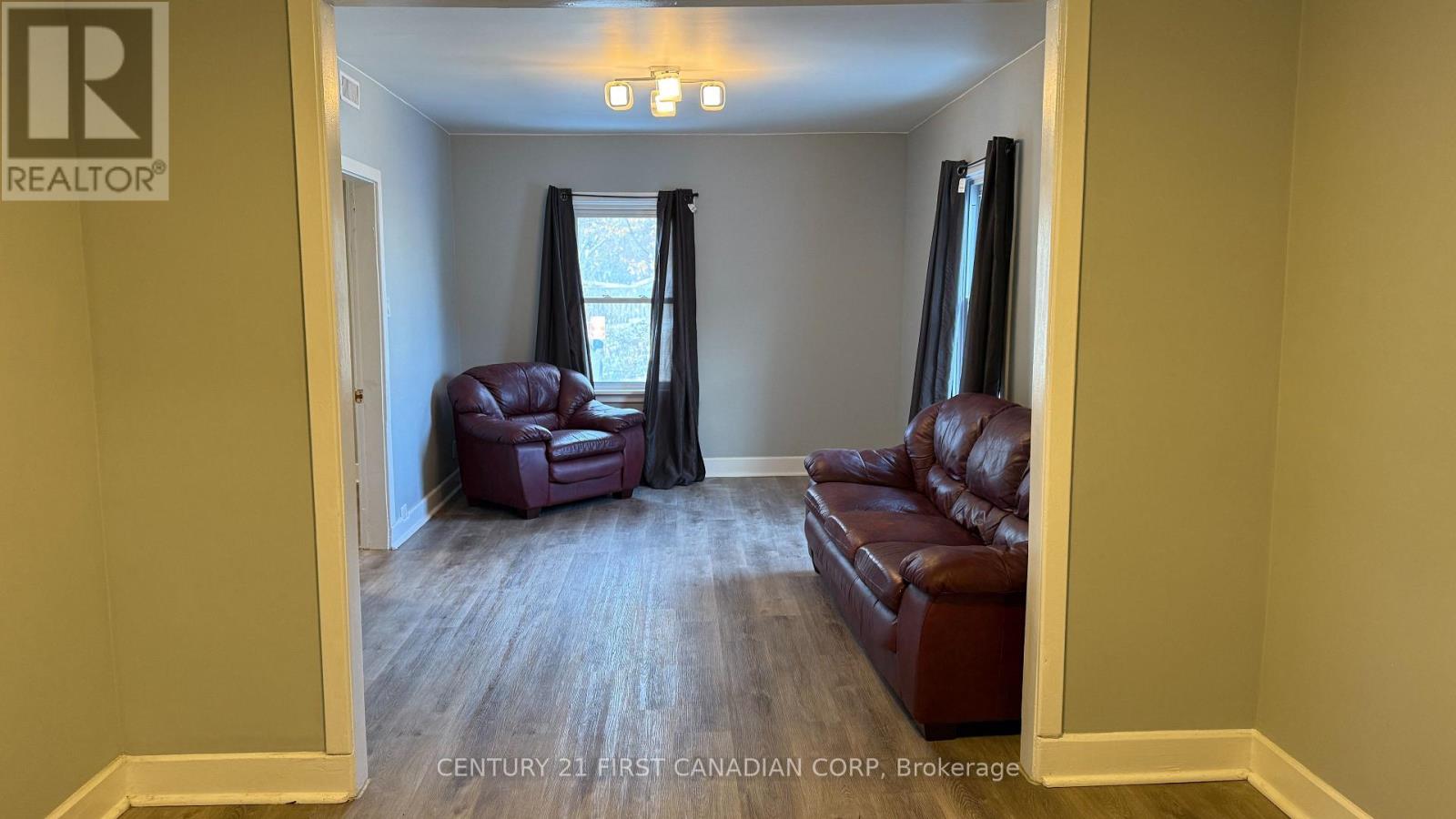 A living room with a brown leather couch and a wooden floor.