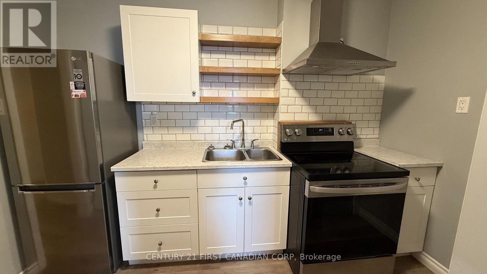 A kitchen with a refrigerator, oven, and sink.
