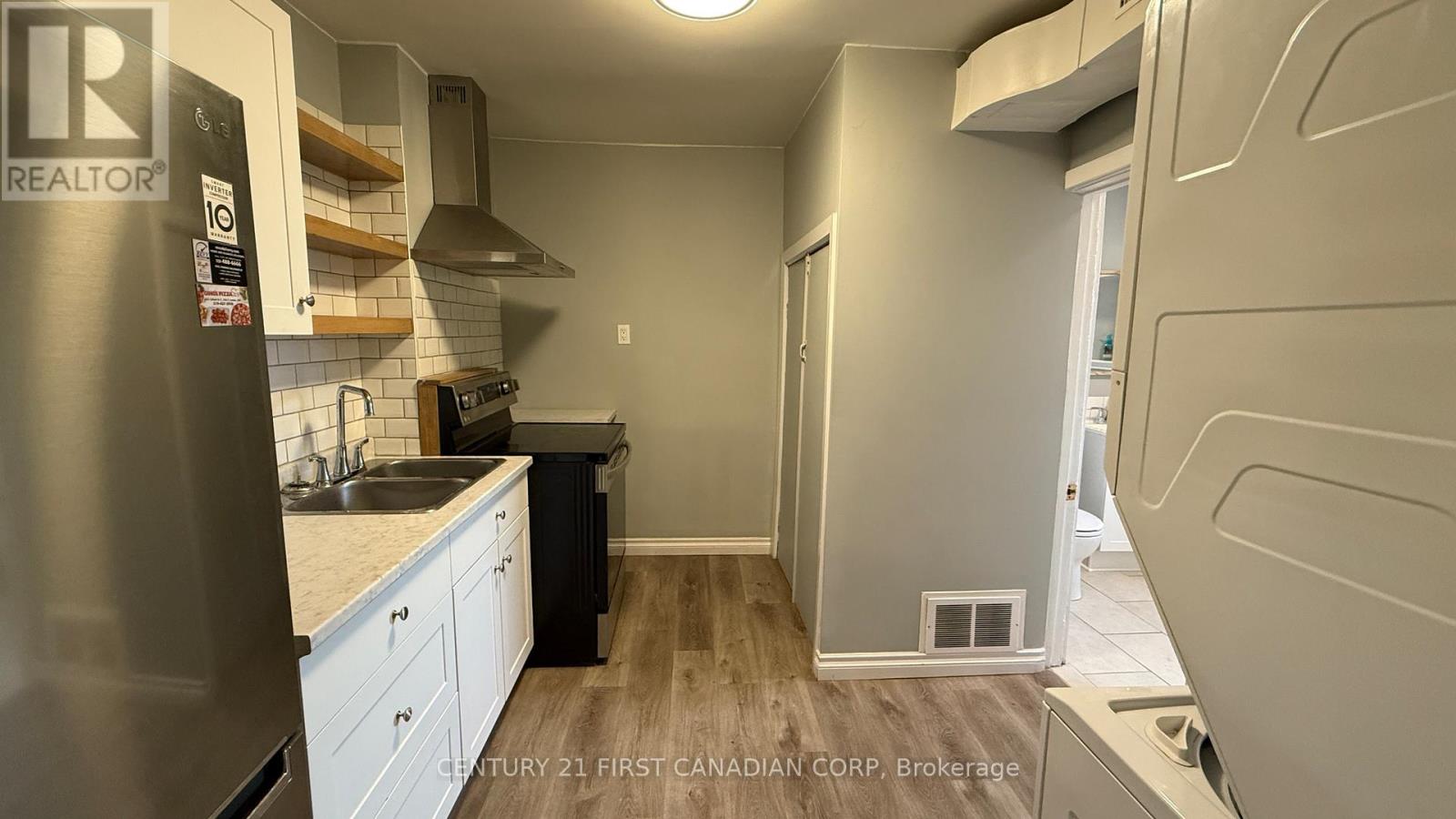 A kitchen with a refrigerator, sink, and cabinets.