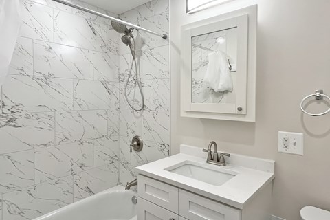 A white bathroom with a marble tile shower.