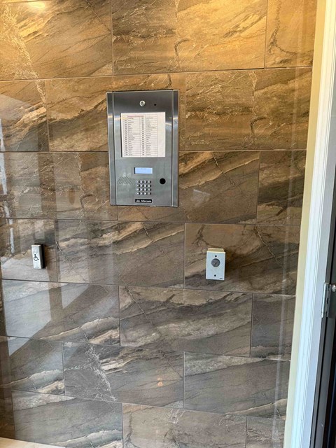 A wall-mounted thermostat and control panel is installed on a marble wall.