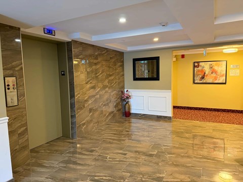 A hallway with a marble floor and a white door.