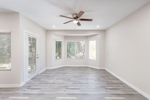 A spacious room with a ceiling fan and sliding glass doors.