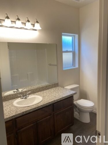 A bathroom with a sink, toilet, and mirror.