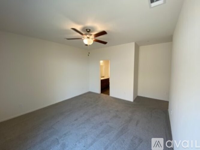 A room with a ceiling fan and carpeted floor.