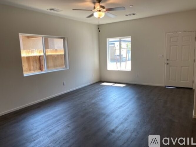 A room with a ceiling fan and two windows.