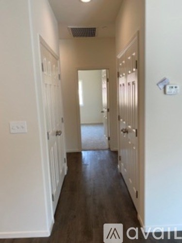 A long hallway with white walls and wood floors.