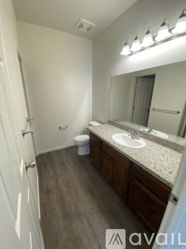 A bathroom with a toilet, sink, and mirror.